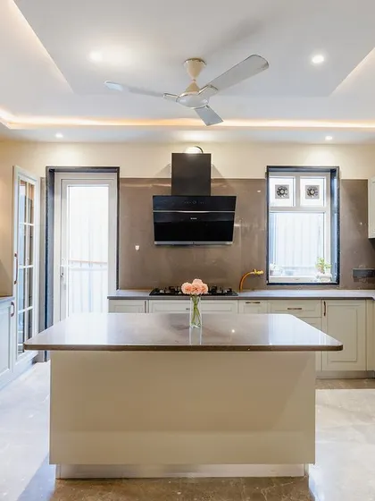 A beautiful and spacious island kitchen. The off-white cabinets with classic molding details give it a timeless look. The central island provides extra counter space and is perfect for meal prep or casual dining.
