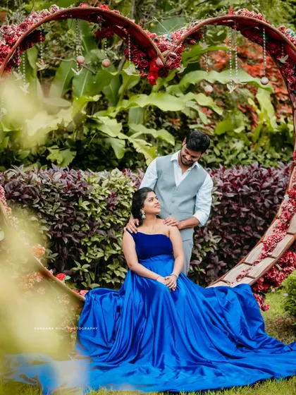 A romantic portrait of a couple framed by a large heart-shaped floral installation in a garden. This image captures the love and anticipation of their journey together.