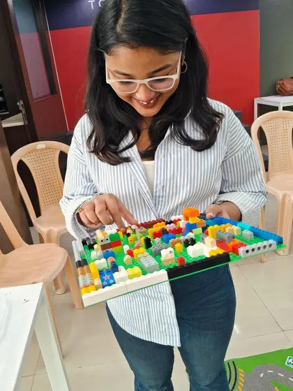 An instructor proudly displays a detailed city block built with LEGOs. Our mentors guide the sessions and also share in the joy of creating complex and imaginative models.