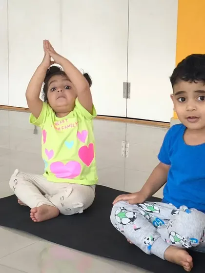 Two children practice a seated yoga pose, showing great focus. Our indoor classes incorporate elements of yoga and stretching to improve flexibility and concentration.