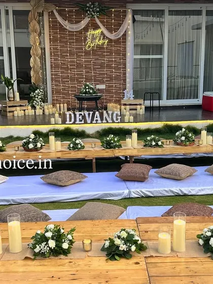 We created a cozy outdoor movie night for a 14th birthday. This unique setup includes low wooden tables with floral centerpieces, comfortable floor seating with cushions on the lawn, and a large projector screen for the main event.