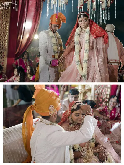 Key rituals from a grand indoor wedding, including the sindoor and holding hands. The warm lighting adds to the traditional and sacred feel of the ceremony.