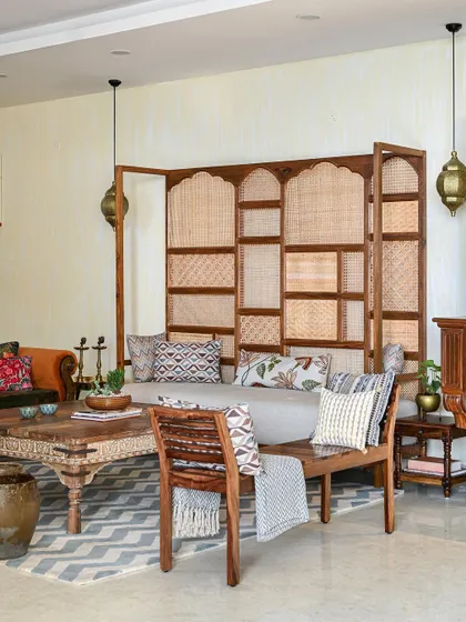 This living room is all about earthy warmth and texture. We used a large teak wood sofa with a custom cane headboard and layered various embroidered fabrics to create a cozy, bohemian-inspired seating area.