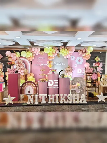 A beautiful fairy-themed party for Nithiksha's third birthday. The setup uses a soft color palette of pink and yellow, with a custom backdrop, rustic props like wooden crates, and large 'ABC' blocks for a playful touch.
