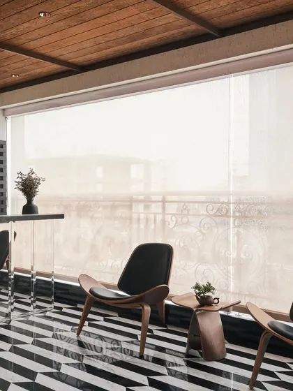 The balcony at Acropolis functions as an extension of the living room, with a retractable screen for all-weather use. The custom black-and-white chevron marble flooring adds a bold, graphic element to the space.