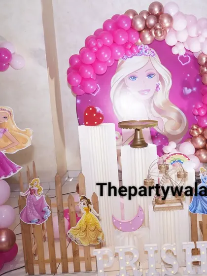 This Barbie party setup features multiple princess cutouts and a picket fence, creating a lovely scene for a 6th birthday celebration.