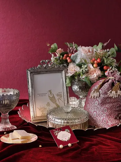 For a touch of royal elegance, the Shimmering Silver hamper is a perfect choice. It combines a silver photo frame, a candle, and a flower arrangement with our mini butter cookies and honey choco almonds.