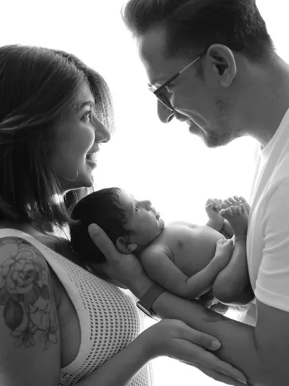 A beautiful black and white portrait of a family. The mother's smile and the father's gentle gaze at the baby create a picture of pure happiness.