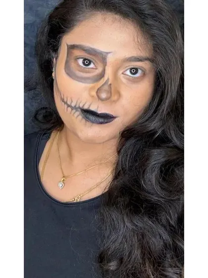 A half-face skull design for a high-impact Halloween or character look. This makeup creates a striking illusion by contrasting a natural face with a detailed skeletal structure on the other side.