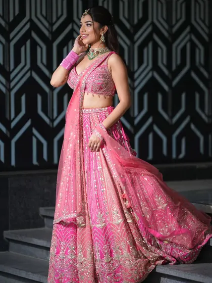 This vibrant pink lehenga is a modern take on the classic bridal look. It’s perfect for a day wedding or sangeet, featuring intricate silver and pink embroidery.
