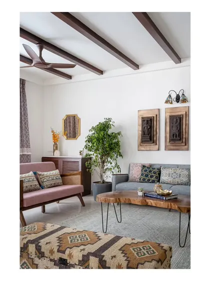 The living area, designed with a warm and rustic ambiance. The space features a mix of comfortable sofas, a unique sandalwood center table, and Indian art elements that blend with the Spanish country theme.