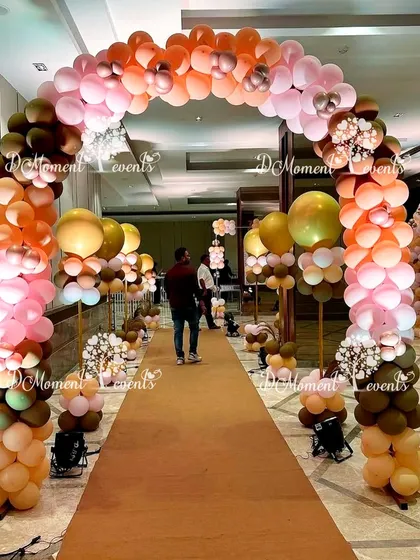 A beautiful balloon archway in earthy and pastel tones lines the entrance path, creating a warm and inviting welcome for guests.