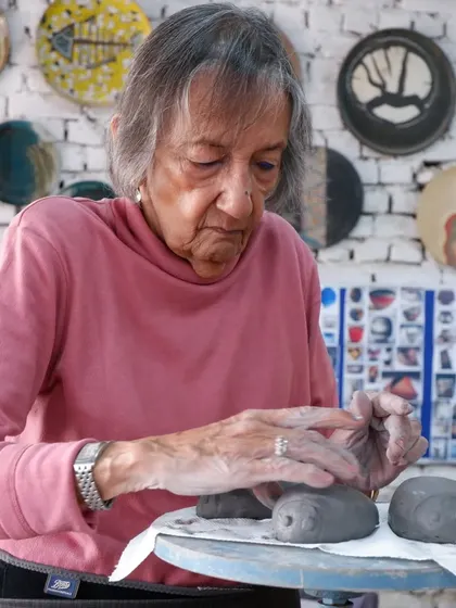 A student carefully works on small, eye-like sculptures, preparing them for the Raku firing. Even small pieces can have a big impact with this technique.