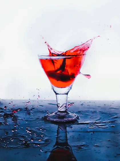 A dynamic splash shot of a red beverage in a cocktail glass. Freezing the motion of the liquid creates an energetic and exciting image, perfect for a drink menu or promotional ad.
