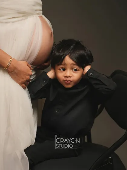 A funny and adorable shot of the older brother to be, covering his ears as he sits by the baby bump. It’s a playful take on the coming changes.