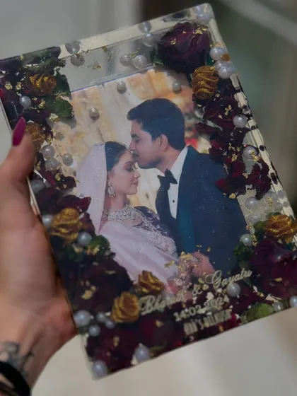 A truly romantic keepsake. This rectangular photo frame captures a beautiful moment between the couple, surrounded by deep red and yellow roses from their wedding. The pearls add a touch of classic elegance.