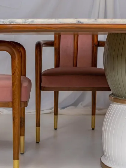 A detail shot of the 'Damru' dining table and 'Svelte' chairs, showcasing the blend of wood, brass, and PU materials.