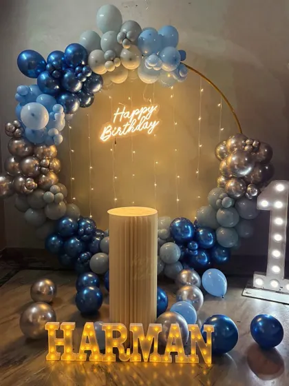 Lighting can transform a celebration, as seen in this first birthday party for Harman. We provided large, light-up marquee letters for the baby's name and age, paired with a 'Happy Birthday' neon sign and a blue and silver balloon arch to create a stunning photo corner.