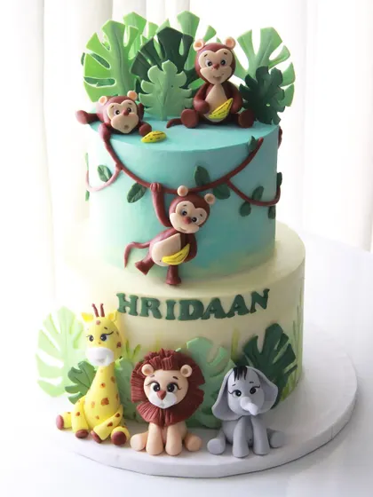 A two-tiered jungle theme cake for Hridaan's 1st birthday. I created a playful scene with monkeys swinging from vines and other friendly animals gathered at the base.