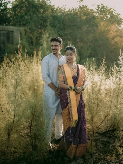 A beautiful outdoor portrait of a Maharashtrian couple standing in a field of tall grass at golden hour.