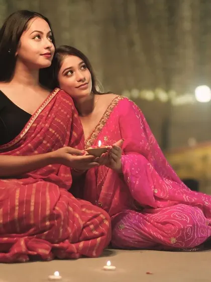 Looking up towards the light, this portrait of two friends captures a sense of hope and shared joy during the magical night of Dev Deepawali.