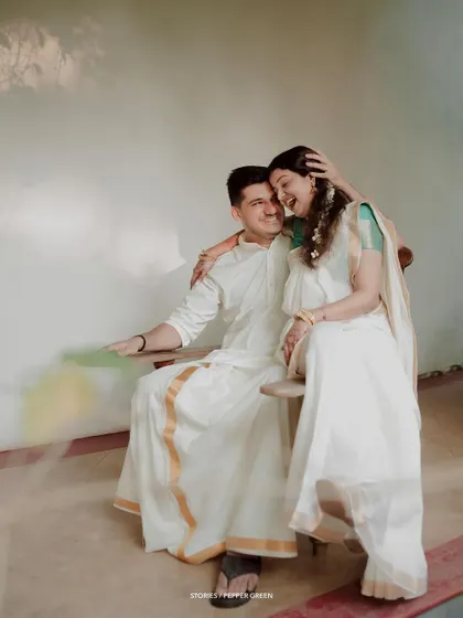 Jayaram and Abirami share a laugh during their traditional Kerala-themed pre-wedding shoot. The classic white and gold attire against a simple backdrop creates a pure and elegant aesthetic.
