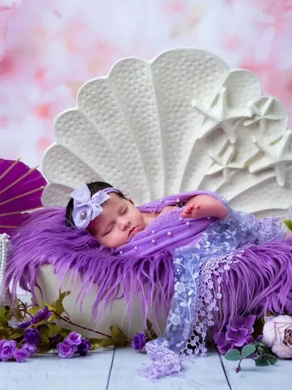 A wide shot of the purple shell theme, showing the newborn sleeping peacefully. The setup includes a purple parasol and pearls, creating a rich, royal look.