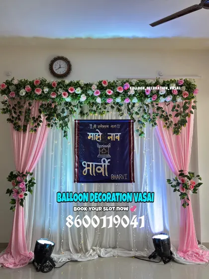 A traditional Marathi naming ceremony (Barsa) backdrop. The setup includes elegant pink drapes, floral arrangements, and a custom banner in Marathi that says "Majhe Naam" (My Name) with the baby's name, Bharvi.