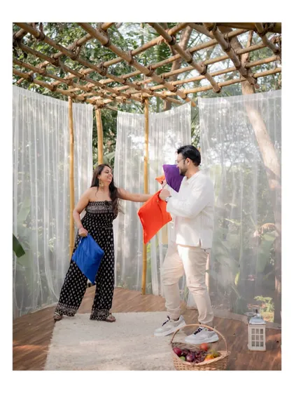 A fun shot of the couple having a pillow fight in a rustic, outdoor canopy setting, capturing their joyful and carefree spirit.