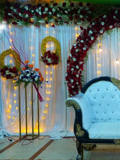 An alternate view of a classic red and white floral stage setup, showing the placement of the sofa, lighting, and decorative stands.