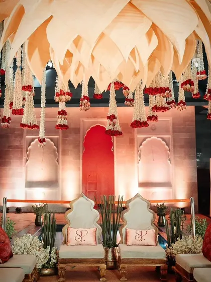 A closer look at the wedding mandap decor, featuring lotus motifs, personalized cushions, and a rich maroon and ivory color palette.