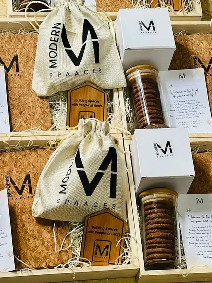 Preparing a bulk order of employee welcome kits. Each hamper for 'Modern Spaaces' is consistently arranged with branded items to ensure every new joiner receives the same warm welcome.