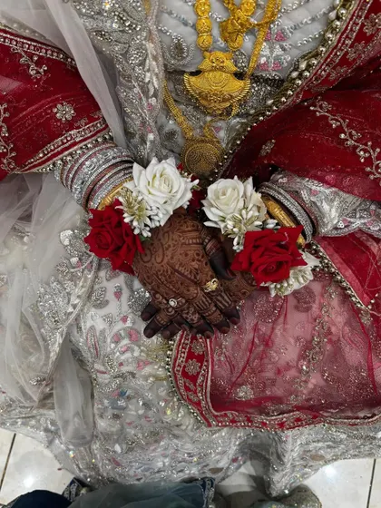 A full view of the bride in her engagement attire, where the dark mehendi stain provides a stunning contrast against her light-colored dress and jewelry.
