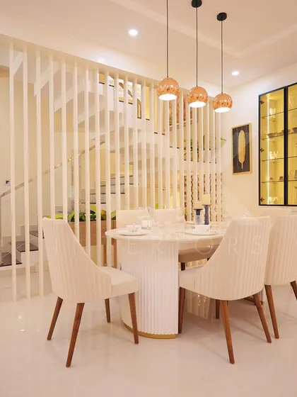 The dining area of the Ernakulam project, featuring a white slatted partition next to the staircase and a glass-front crockery unit with internal lighting.