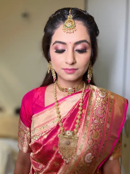 A close-up of a South Indian bride, showcasing a soft pink smokey eye and elegant gold jewelry.
