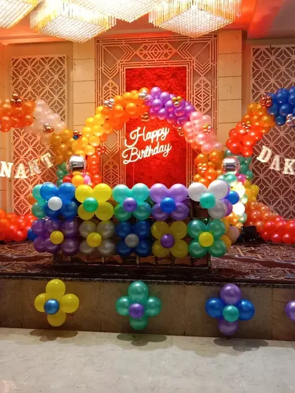 A colorful double balloon ring setup on a stage. This decoration uses bright, rainbow-colored balloons and flower-shaped clusters to create a fun and festive look for a joint birthday party.