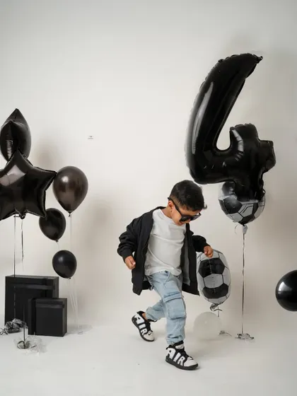 Another playful moment from the fourth birthday shoot, as he interacts with the football-themed balloons. These sessions are all about movement and fun.