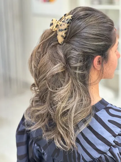 A simple half-up style showcasing a beautiful brunette balayage. The claw clip adds a trendy touch to the soft, wavy look.