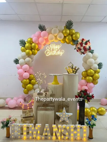 You can't go wrong with a classic and elegant ring backdrop. This setup uses a beautiful mix of pink, white, and gold chrome balloons, a "Happy Birthday" neon sign, and lots of pretty props like a mini Ferris wheel and light-up letters for the name.
