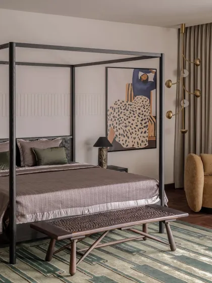 The parent's bedroom in the Aikaa villa, featuring a modern four-poster bed and a bold piece of art. We balanced the strong lines of the furniture with soft textiles and a patterned rug for a sophisticated yet comfortable feel.