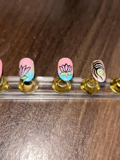 Another view of the hand-painted lotus and peacock feather nails. The blend of pink, blue, and green gives this set a vibrant and artistic feel.
