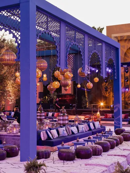 A wide view of the Moroccan-themed Sangeet lounge, showcasing the Majorelle blue structures and clusters of brass lanterns.