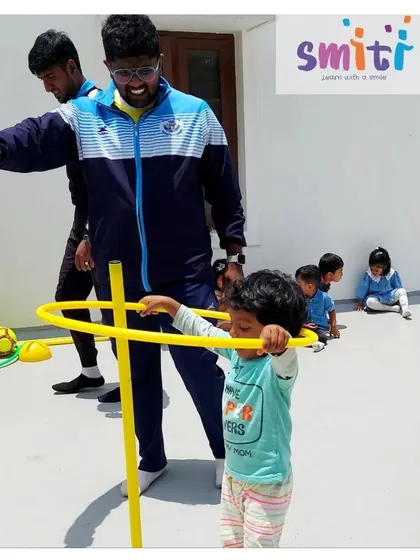 A toddler learns to navigate a hula hoop obstacle. Our physical activities are adapted for all age groups to ensure everyone can participate and have fun.