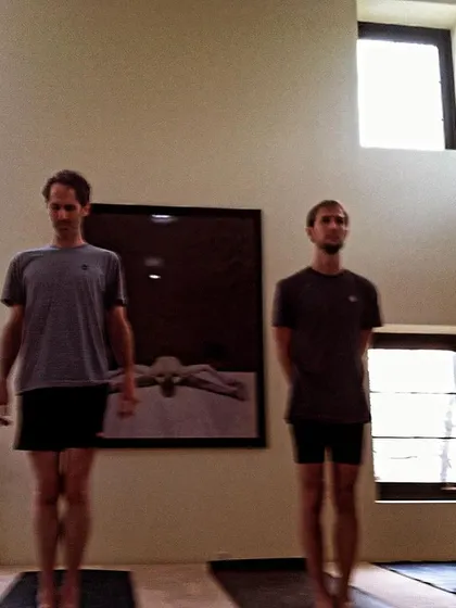 Practitioners standing in Samasthitihi, the foundational pose of equal standing. This moment captures the focus and dedication that are central to the Ashtanga practice.