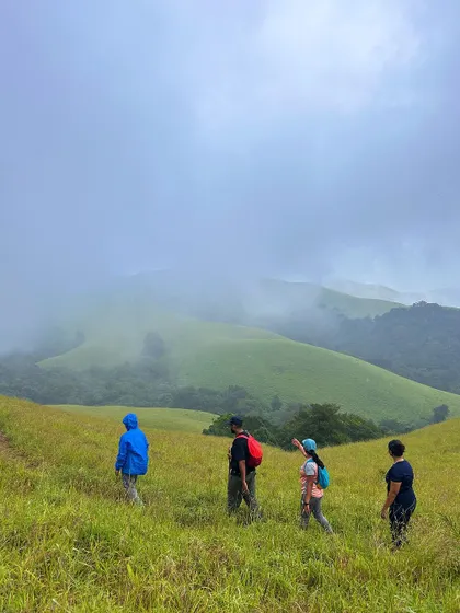 Trekkers walking through the green paradise of Bandaje, with misty mountains in the background.