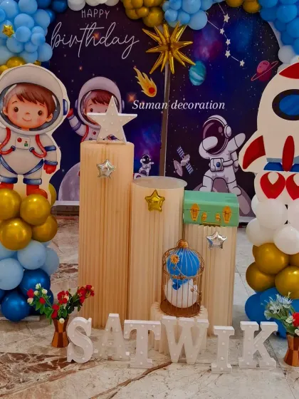 A detailed shot of the space-themed setup, focusing on the astronaut cutout and decorative props on the plinths.