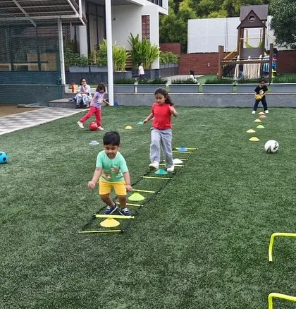 This action shot shows multiple drills happening at once, from agility ladders to hurdles. We keep our classes dynamic and engaging to hold the children's attention.