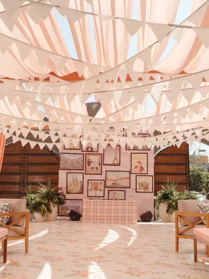 The DJ booth at the Parisian Market Mehendi was set against a photo wall of the couple's travel pictures, with pastel bunting overhead, reinforcing the personal and charming market theme.