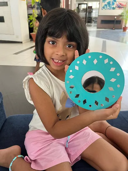 One of our popular activities is decorating these beautiful round mirrors. This young creator is so happy with her unique, colourful design.