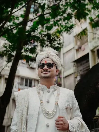 A cool and stylish portrait of the groom, Suraj, in his white sherwani and sunglasses. This shot captures his personality and modern royal look.